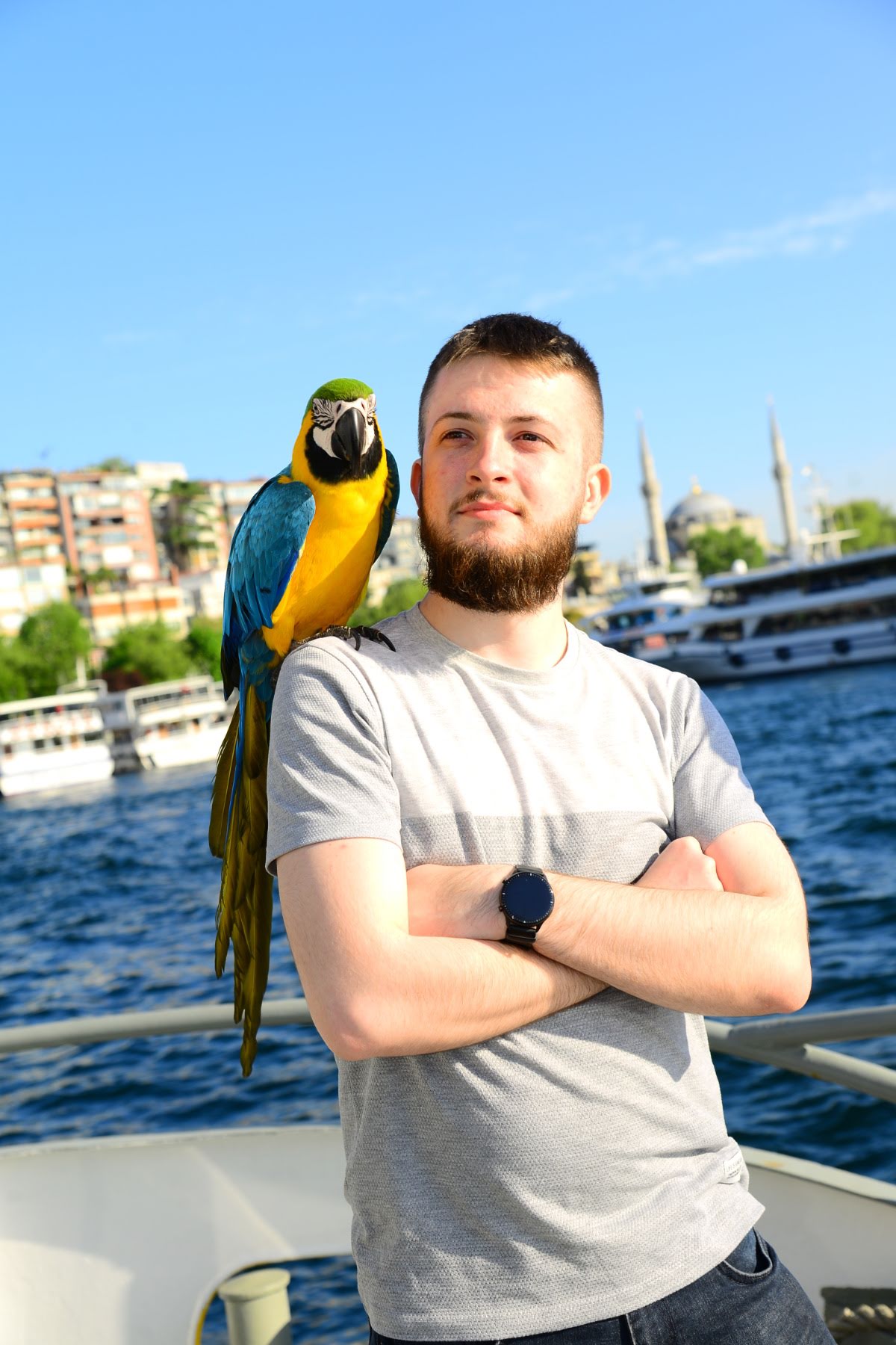 Velid Duranović with a macaw on his shoulder, Istanbul waterfront behind him